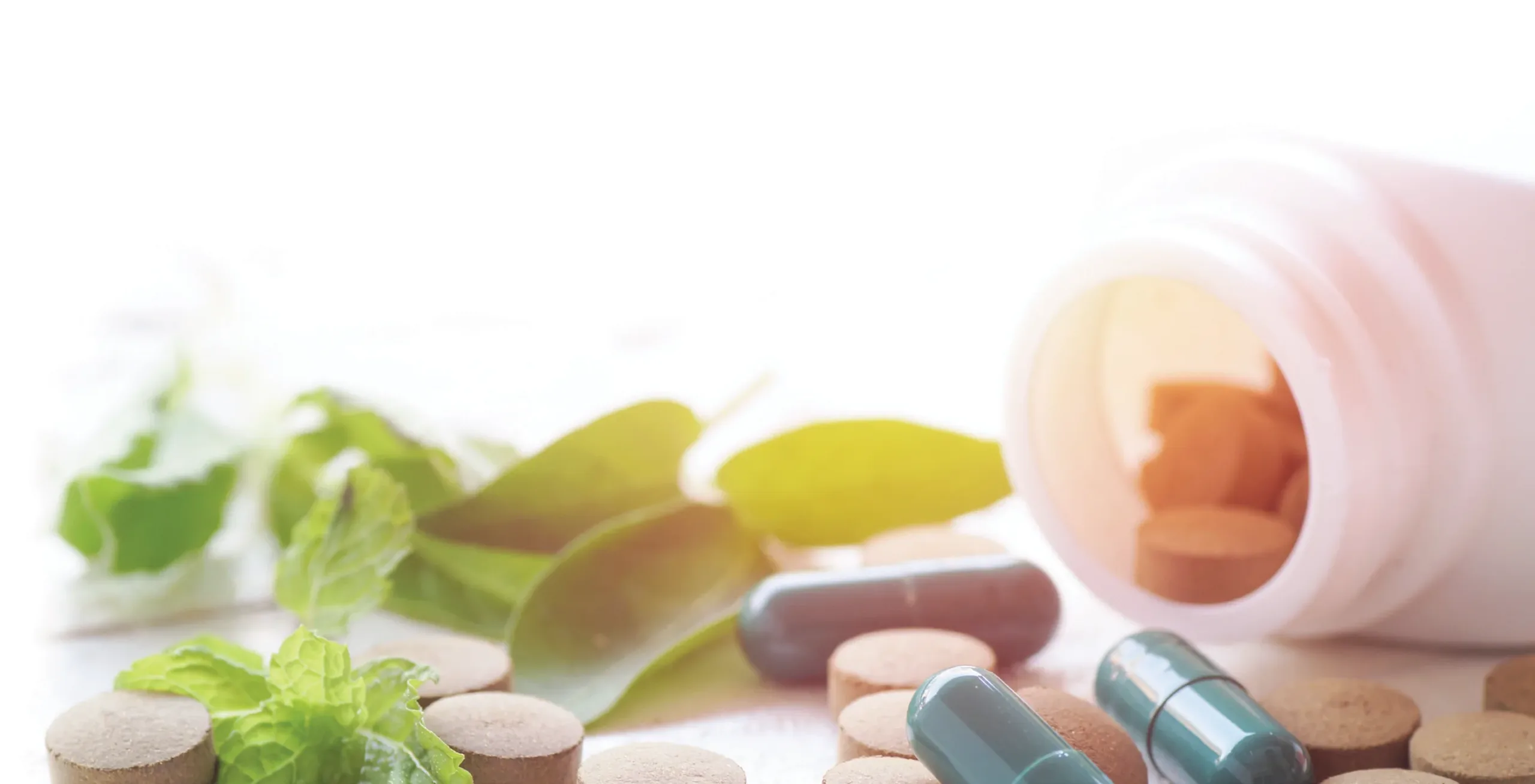 Photo of medicine bottle with supplements among leafy greens